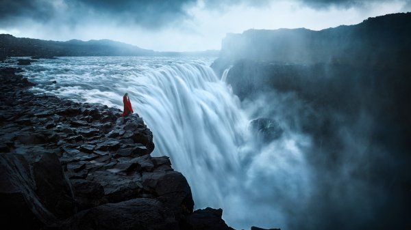 Девушка стоит на фоне водопада, фотограф TJ Drysdale