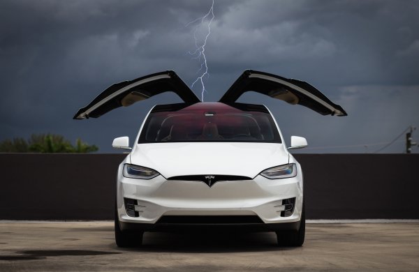 tesla-model-x-white-electric-car-wing-falcon-lighting-clouds