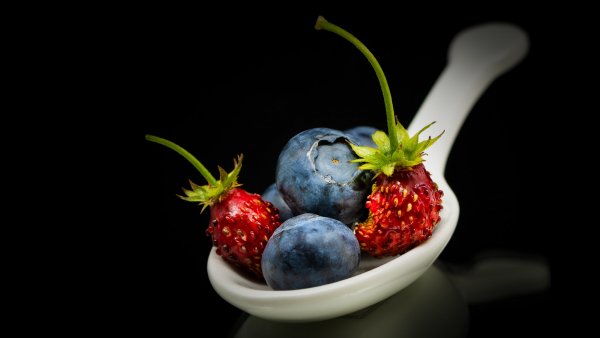 Iagody-chernika-lozhka-chernyi-fon-zemlianika-otrazhenie